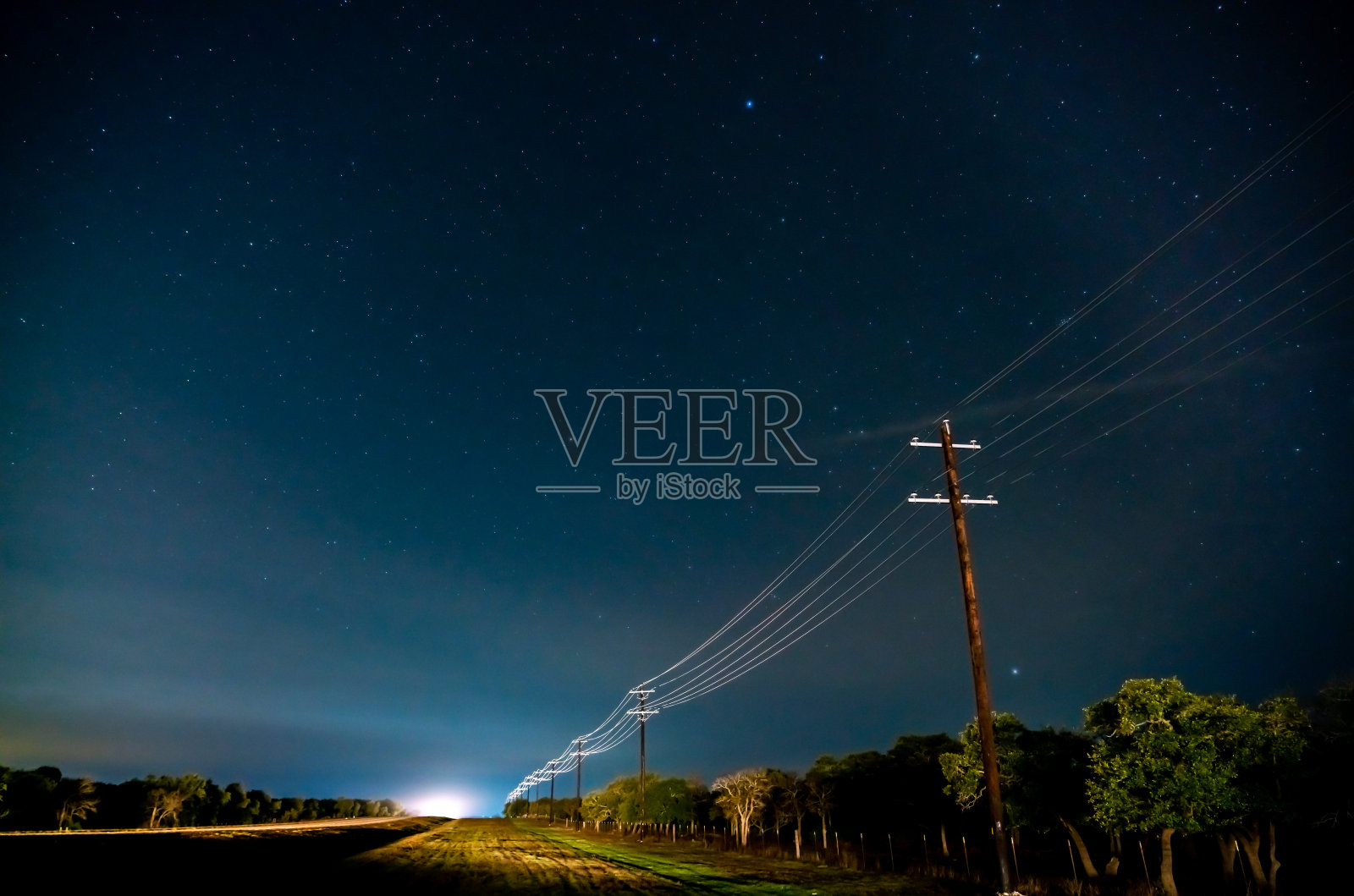 在晴朗的夜空下，被交通点亮的乡村道路照片摄影图片