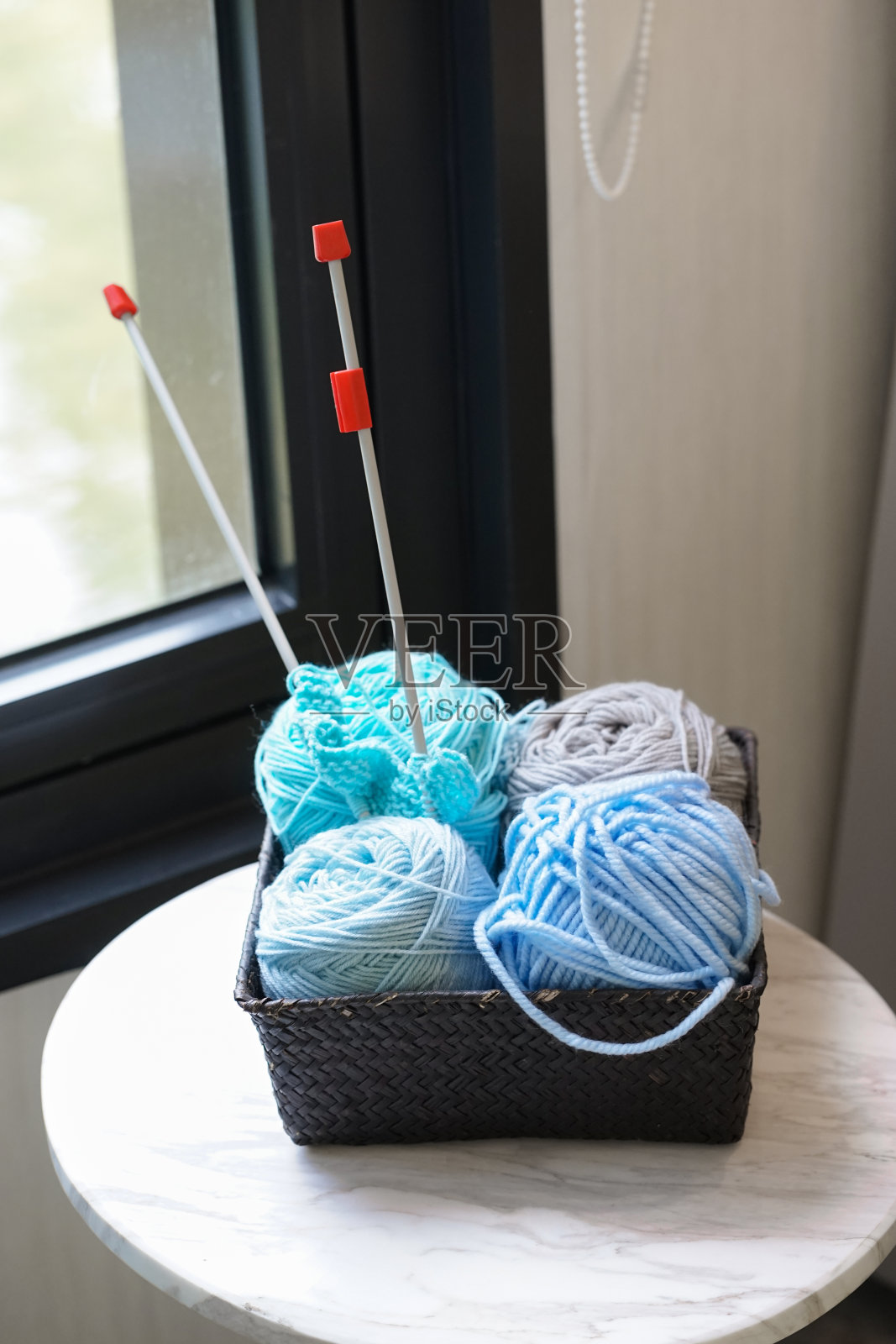 针织纱。窗边放着一篮子深浅不一的蓝色针织品。光的窗口。照片摄影图片