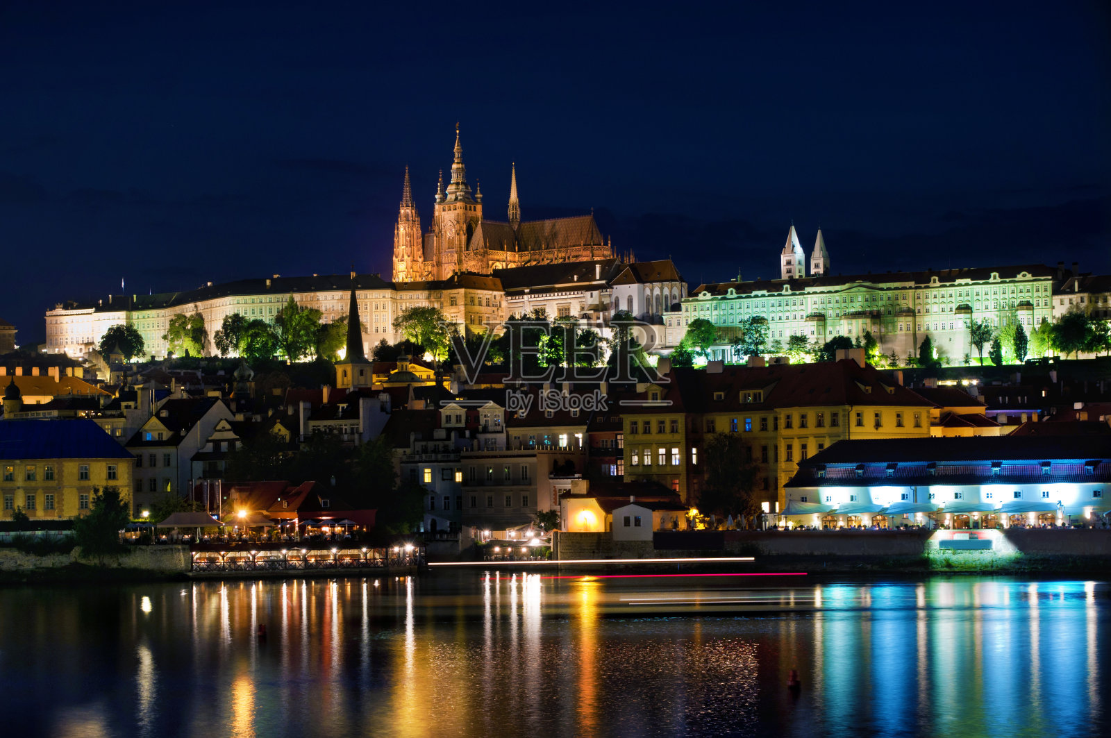 伏尔塔瓦河附近的布拉格城堡和圣维塔斯大教堂有许多小房子，映衬着深蓝色的夜空，水中反射着灯光。布拉格,Chezh共和国照片摄影图片