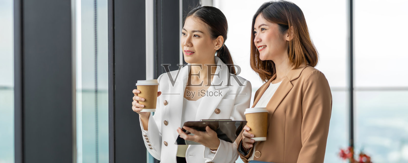 横幅，两个亚洲商业女性在现代办公室或共同工作空间的咖啡休息时间交谈的网页照片摄影图片