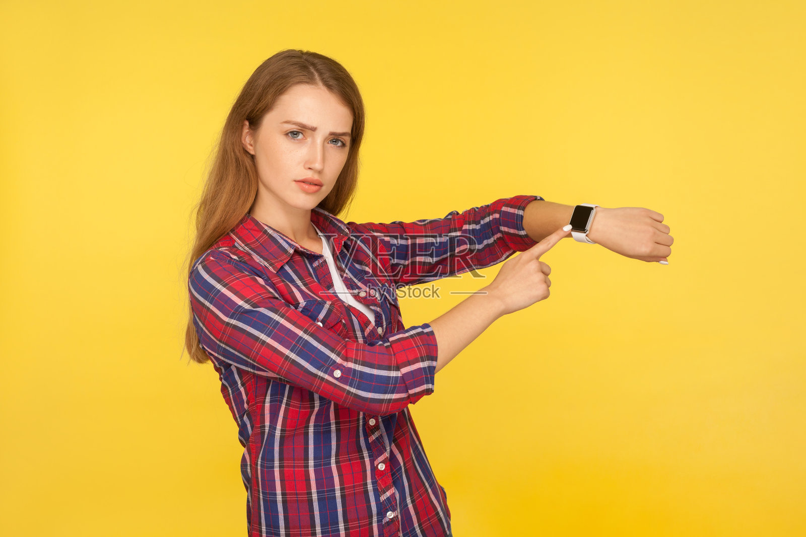 看看时间!肖像严肃的姜黄色女孩在格子衬衫指着手表在她的手腕和看起来不高兴照片摄影图片