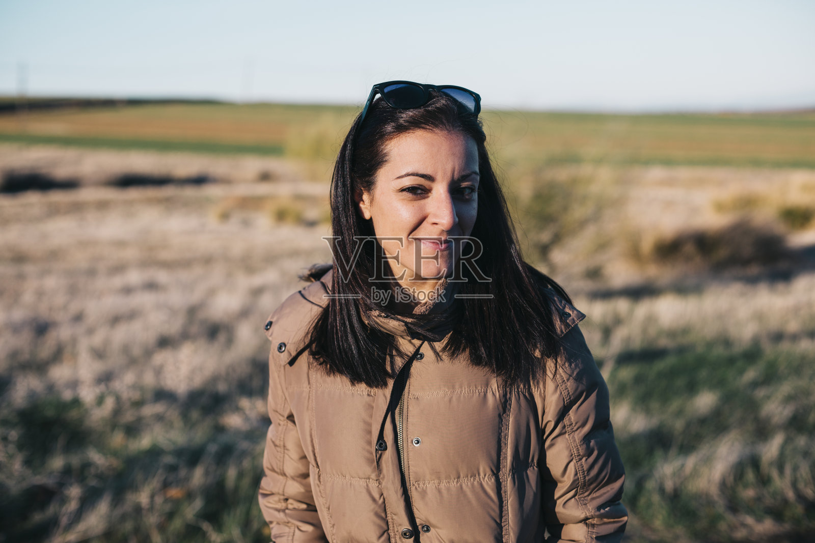 户外肖像的一个年轻美丽的女人在日落。秋季或冬季。她穿着一件棕色的外套。生活方式照片摄影图片