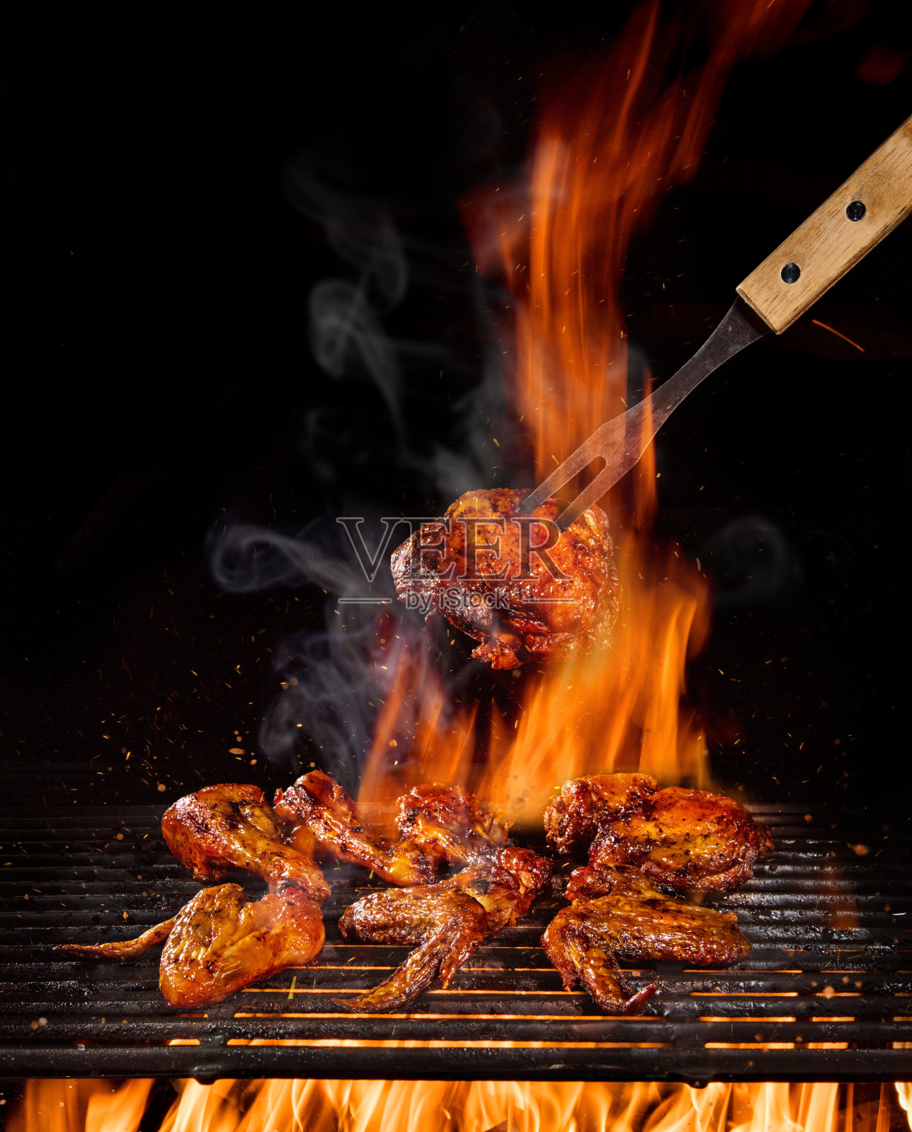 鸡腿和翅膀放在烤架上用火焰烤照片摄影图片