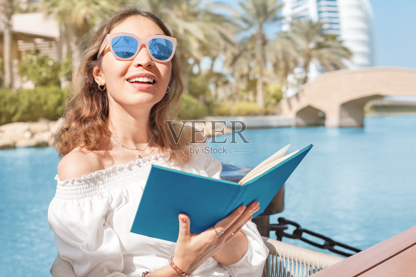 微笑的女孩读菜单在酒吧或餐厅的露台上，同时放松在海边度假照片摄影图片