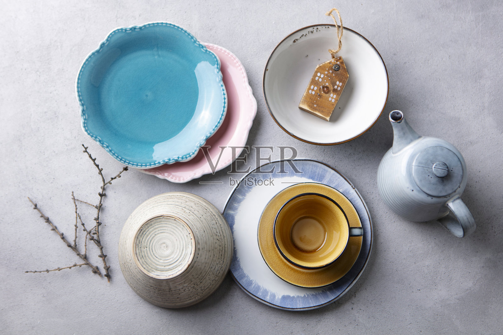 灰色石头背景上的陶瓷餐具、盘子、碗、杯和茶壶。前视图。照片摄影图片