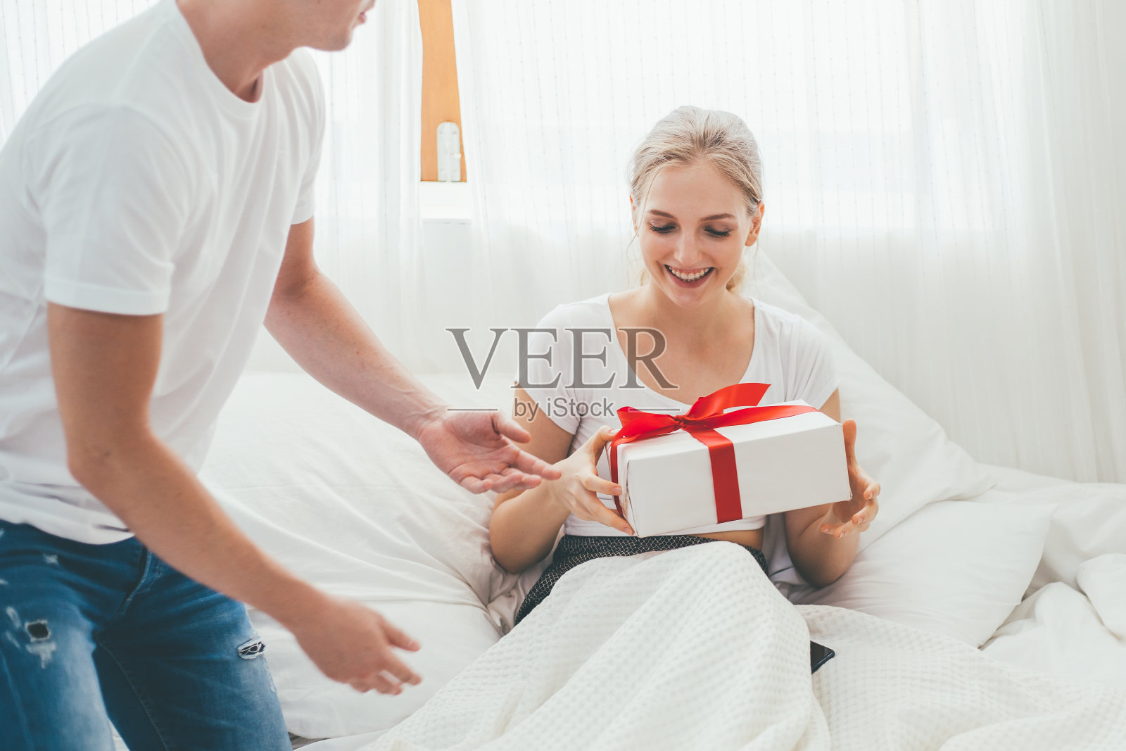 幸福的白人夫妇的爱是在家里的卧室一起庆祝，年轻英俊的男子给他的女朋友礼物盒在情人节，周年纪念，生日或圣诞节惊喜照片摄影图片