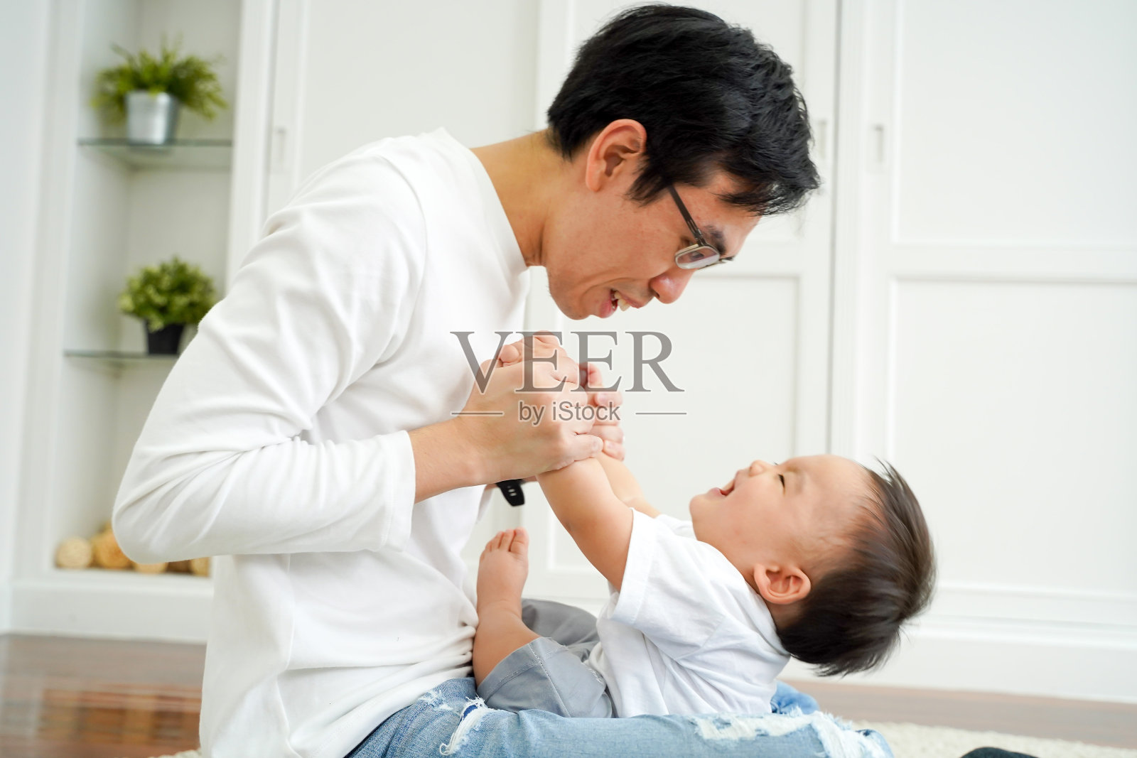 快乐的亚洲父亲和他的小儿子在客厅玩，享受家庭时光照片摄影图片
