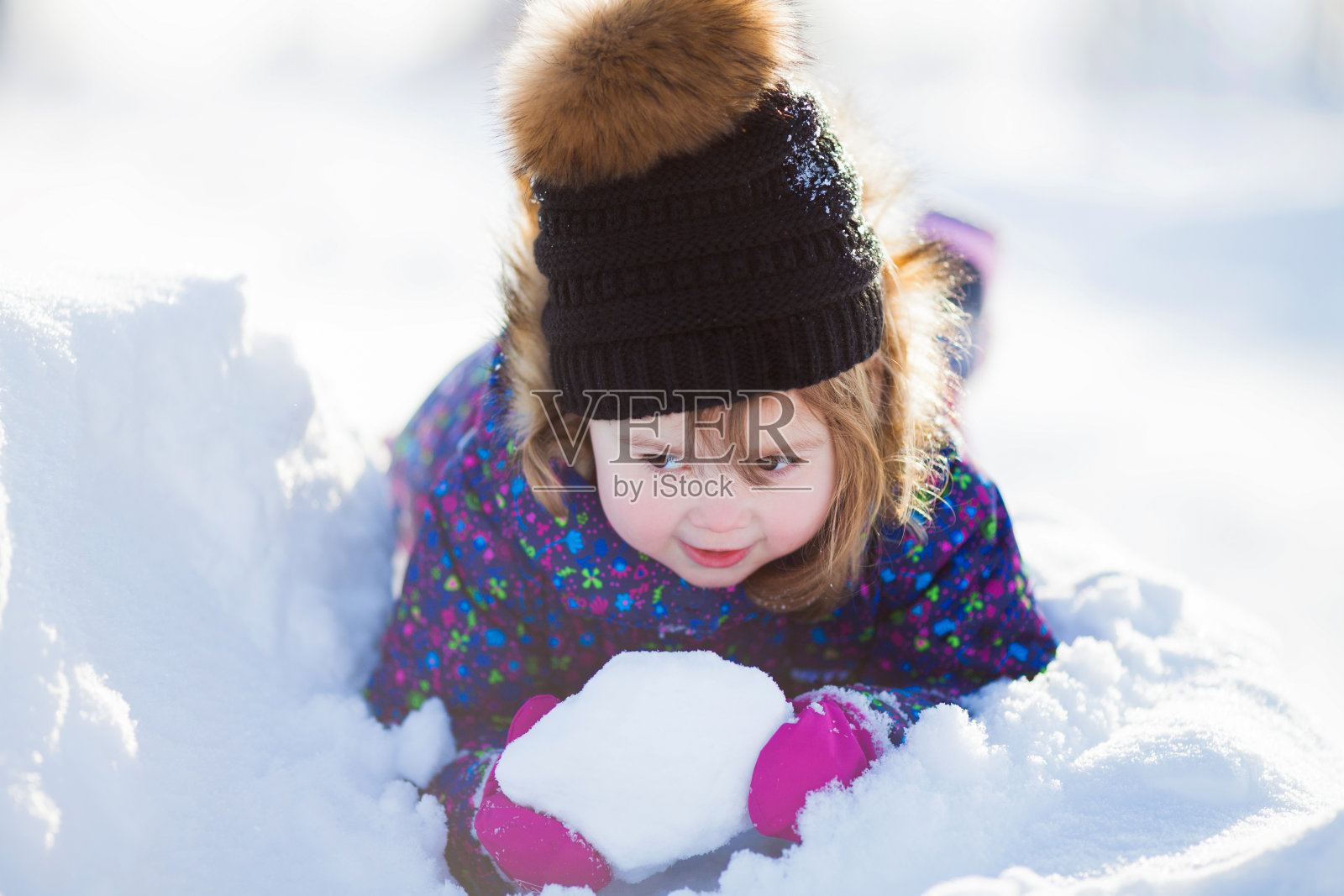 一个可爱的蹒跚学步的小女孩在一个阳光明媚的冬日户外。照片摄影图片