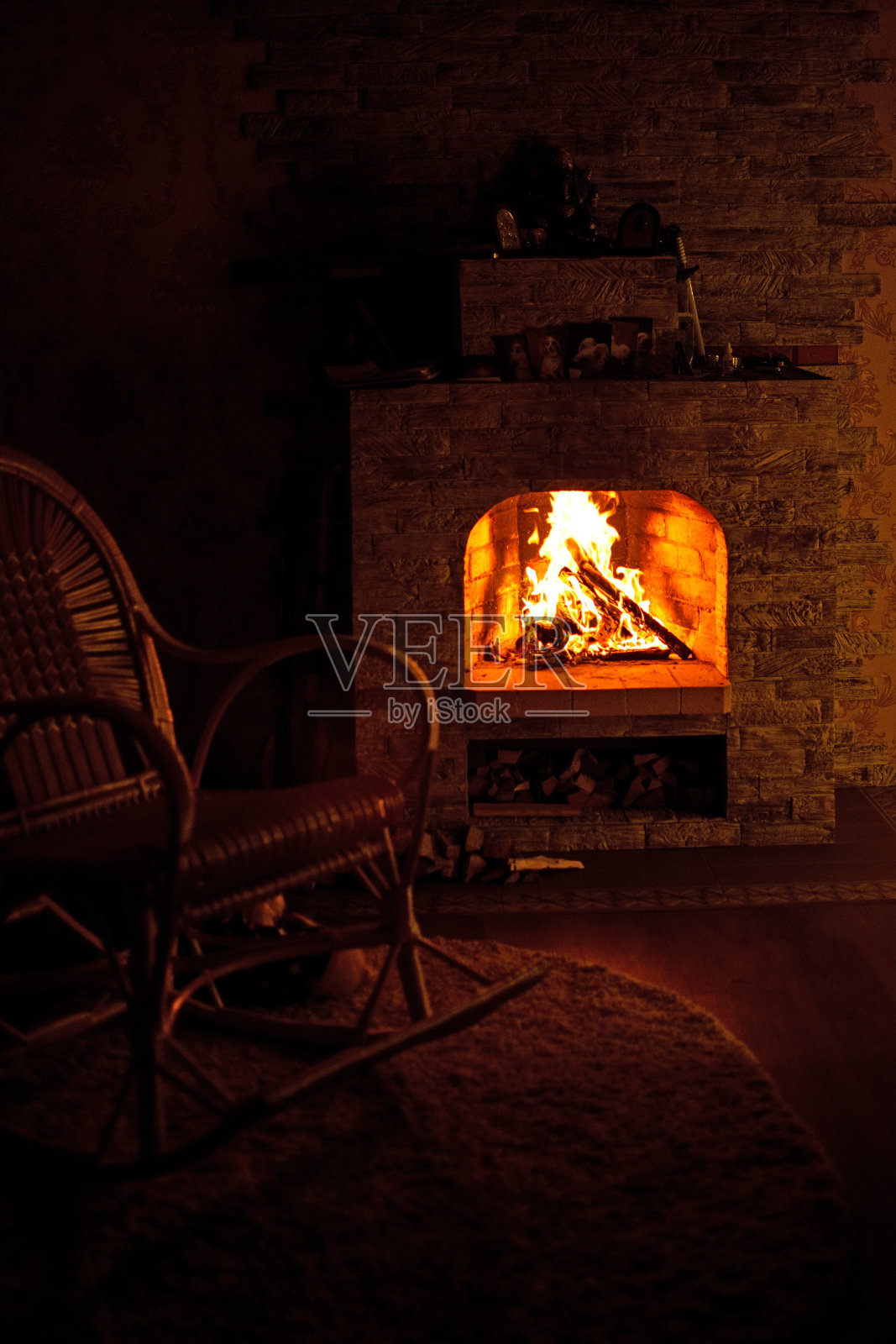 乡村小屋壁炉旁的摇椅。壁炉里的火很暖和。照片摄影图片