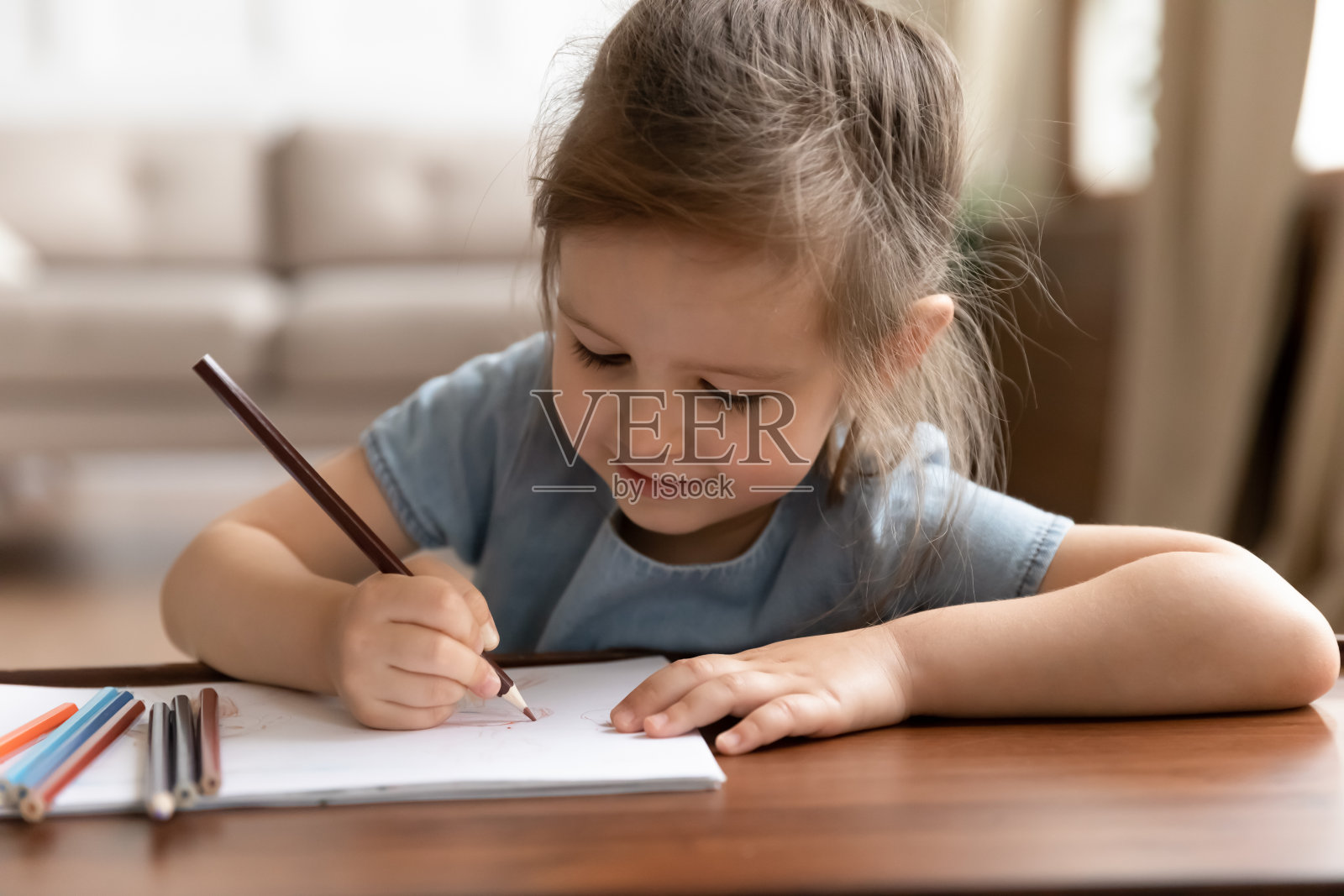 可爱的学龄前小女孩用彩色铅笔画画。照片摄影图片