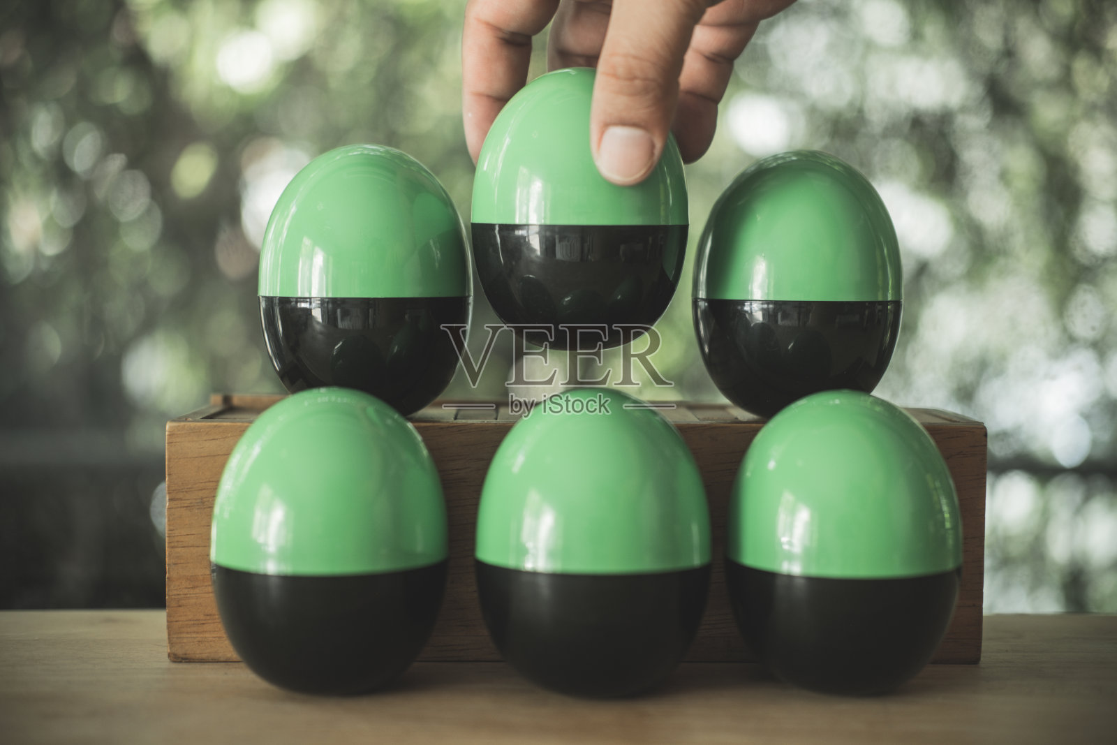 手随机挑选黑色和绿色的塑料鸡蛋或鸡蛋惊喜玩具。鸡蛋惊喜的概念照片摄影图片