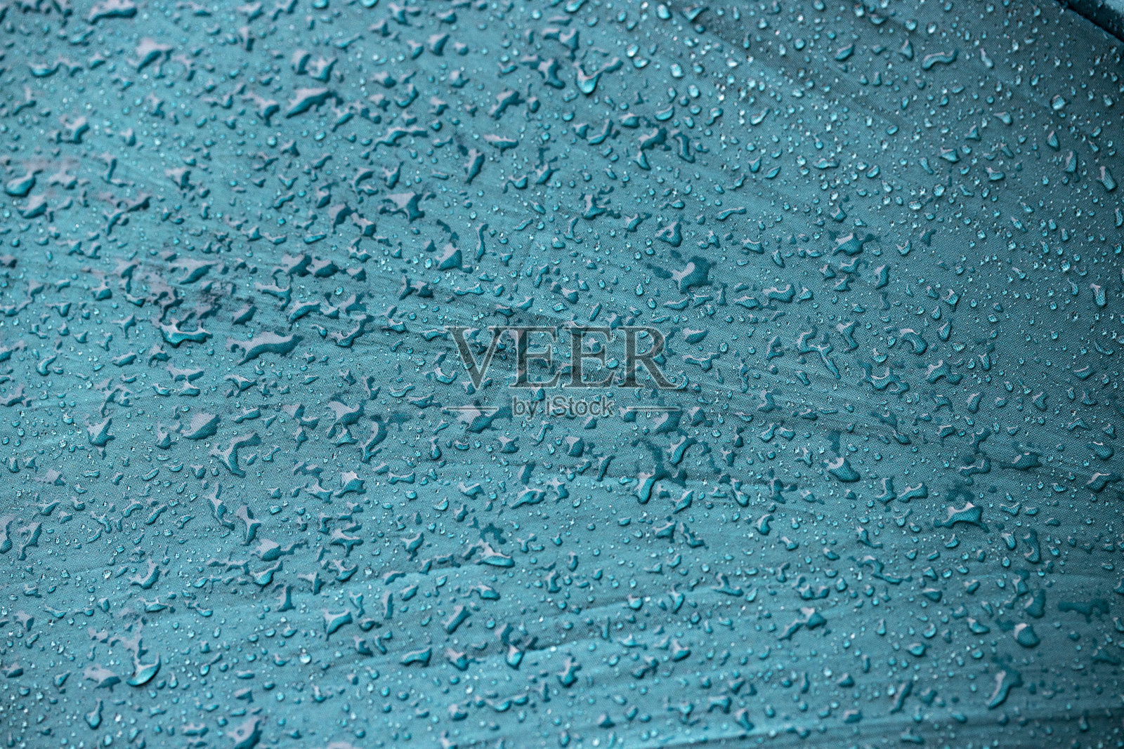 雨水水滴在蓝色纤维防水织物上。照片摄影图片