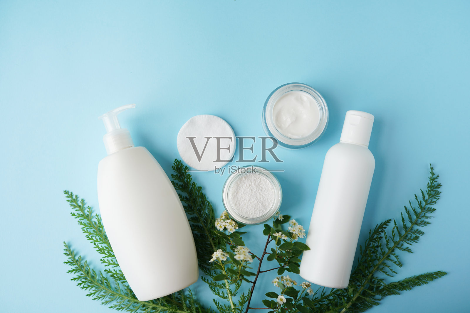 化妆品瓶容器与绿色草药叶子，空白标签的品牌模型，自然美容产品的概念。照片摄影图片