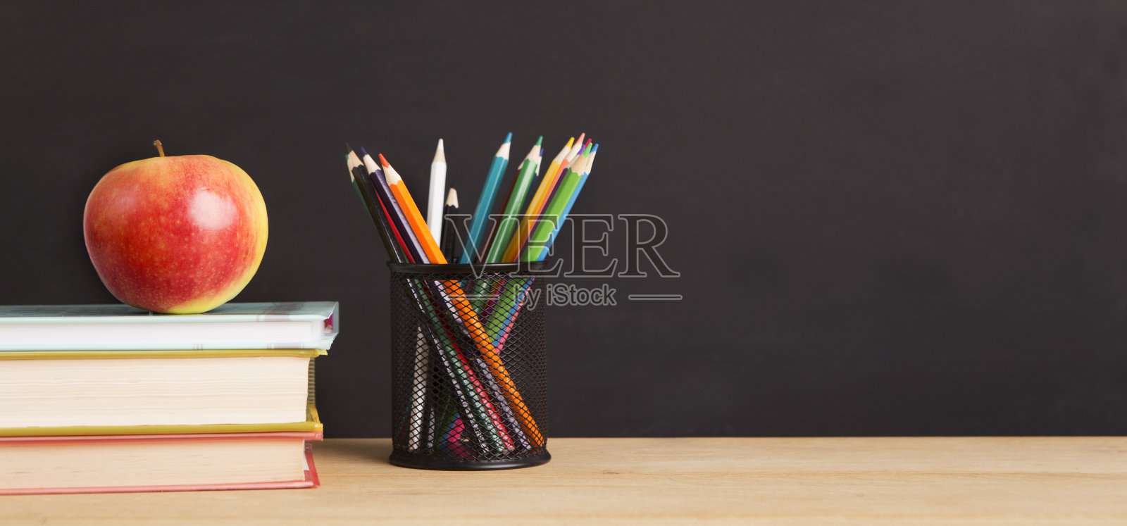 课本，苹果和铅笔放在黑板的背景上照片摄影图片