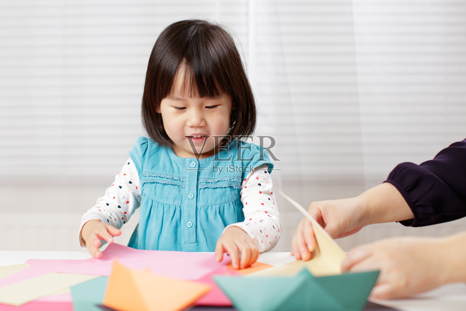 小女孩在家学习折纸，背景是白色照片摄影图片