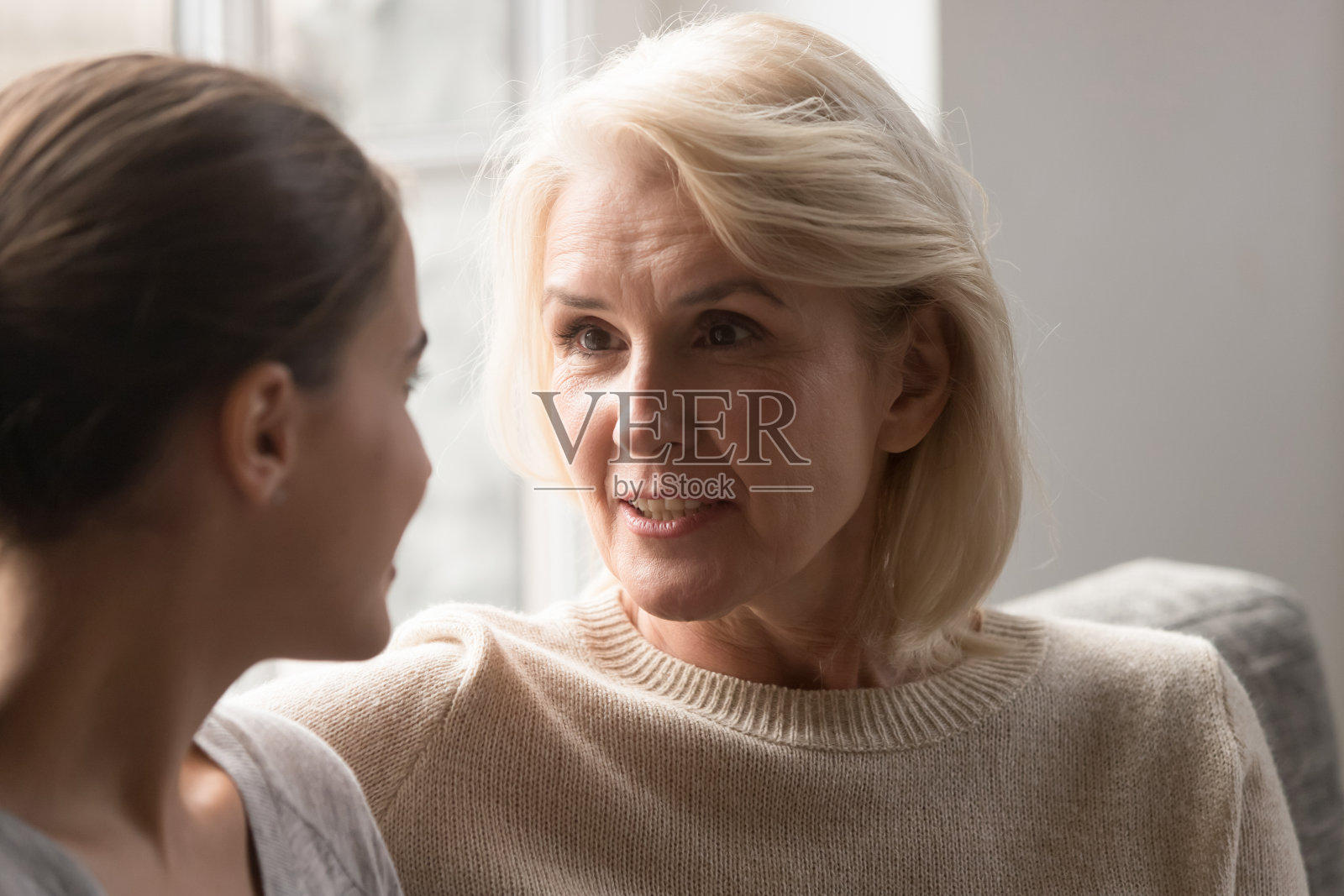 年迈的母亲坐在沙发上和成年的女儿聊天照片摄影图片