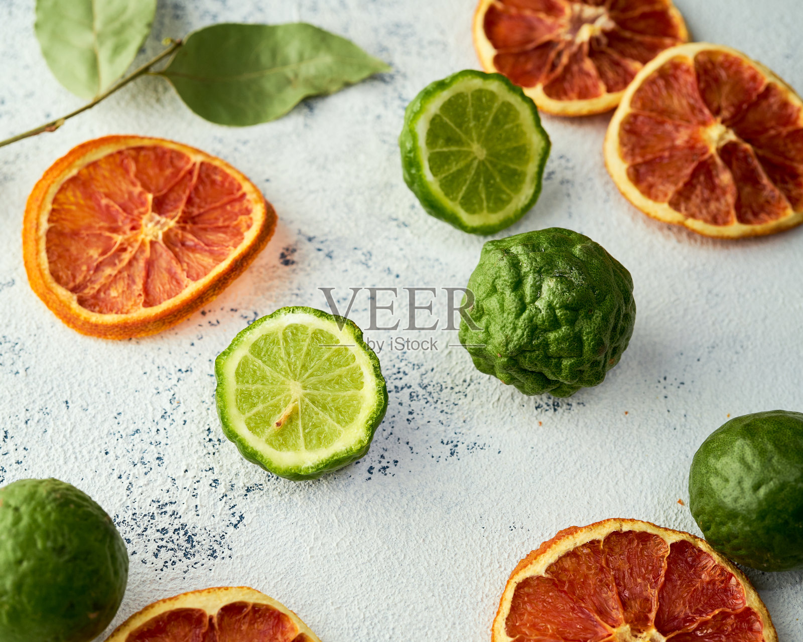 混合了血橙片和新鲜的卡菲尔酸橙在浅色的背景上照片摄影图片