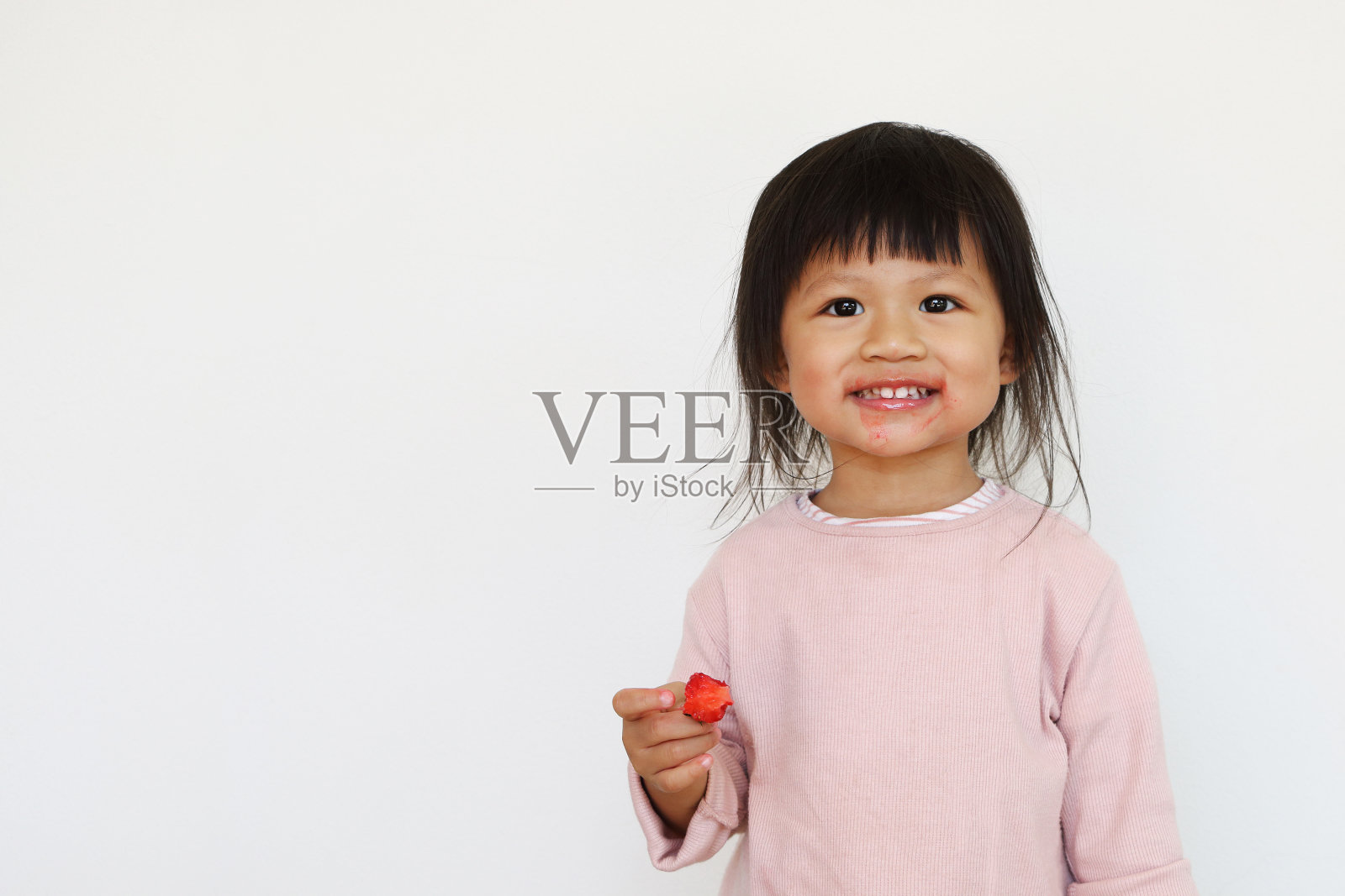 微笑的亚洲女孩喜欢吃红草莓和有脏的脸照片摄影图片