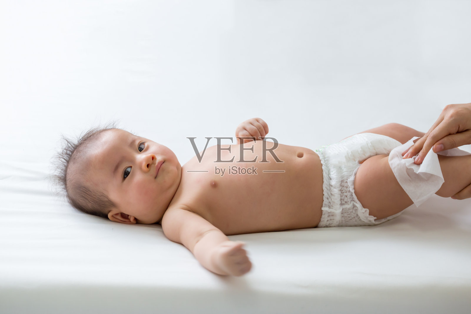 妈妈在给宝宝换尿布时用湿纸巾擦身体，擦手、脸或腿，用湿纸巾擦妈妈和蹒跚学步的孩子的个人卫生概念照片摄影图片