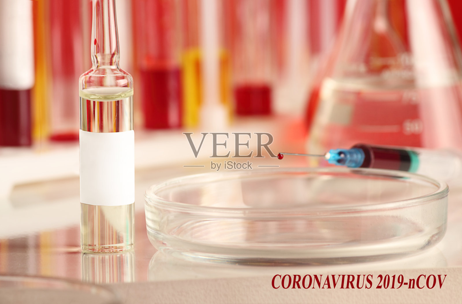 在医用安瓿和实验室玻璃器皿的背景上带有血液样本的注射器。病毒流行，医学概念与题词——冠状病毒2019-nCOV。照片摄影图片