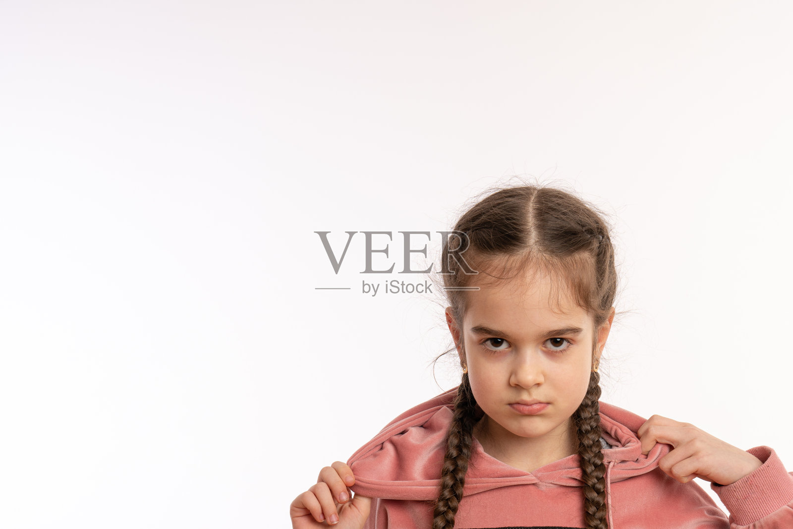 近距离的照片，一个沮丧，愤怒的小女孩的辫子孤立在白色的背景照片摄影图片