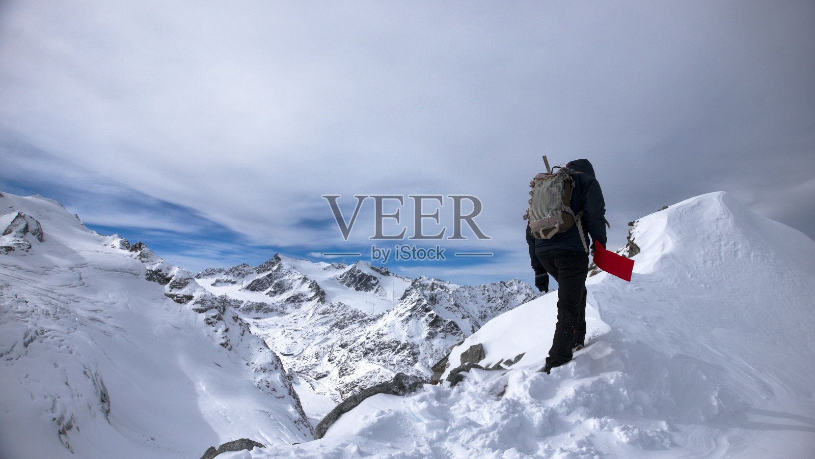 男子攀登者到达岩石顶峰在深雪中携带红旗附近的雷滕巴赫冰川SÃ¶lden Tirol奥地利在蓝天阴天照片摄影图片