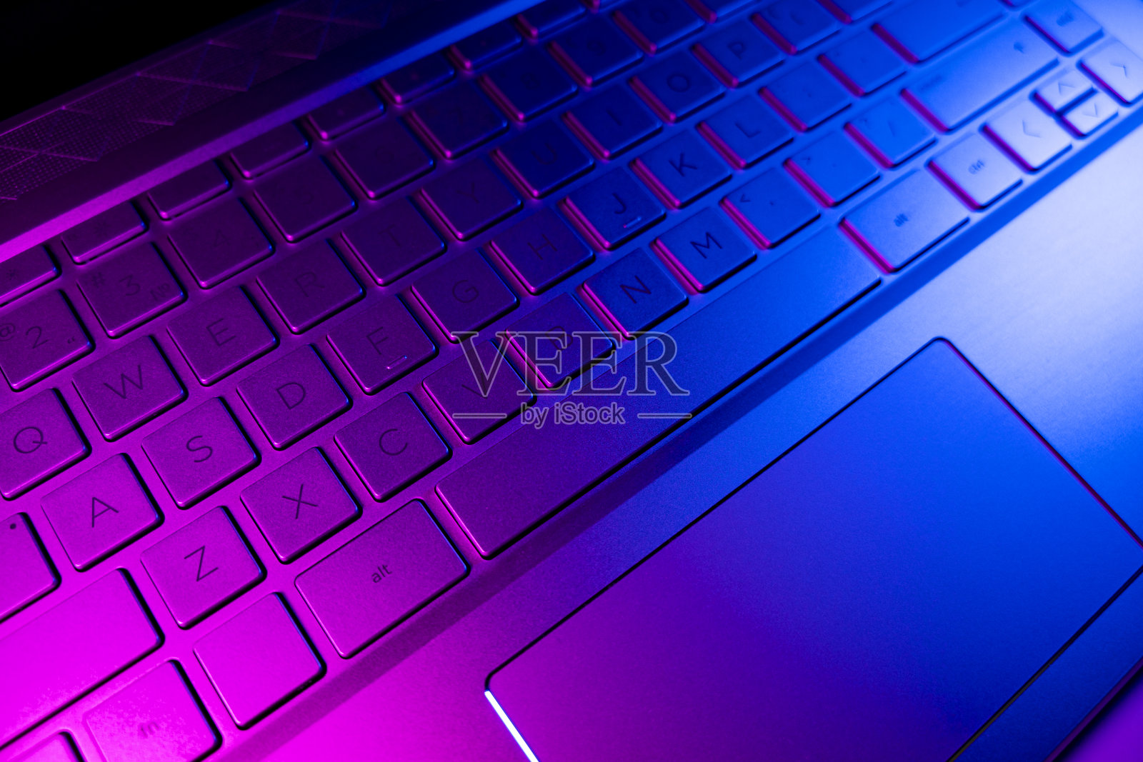 近景现代笔记本电脑键盘键。柔软的闪电。电脑键盘关闭在粉红色和蓝色调照片摄影图片