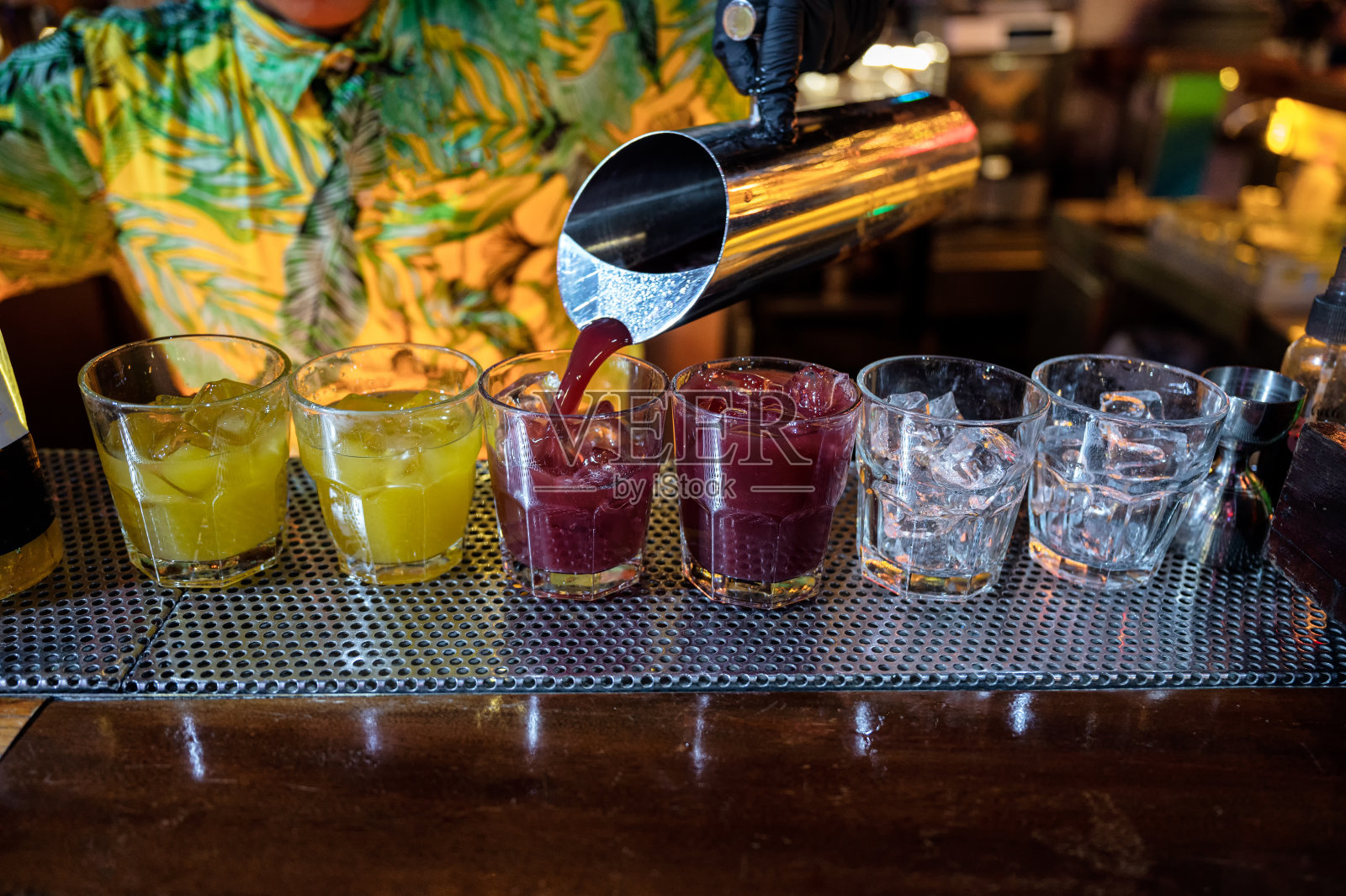 调酒师将鸡尾酒水果倒入加冰的玻璃杯中照片摄影图片