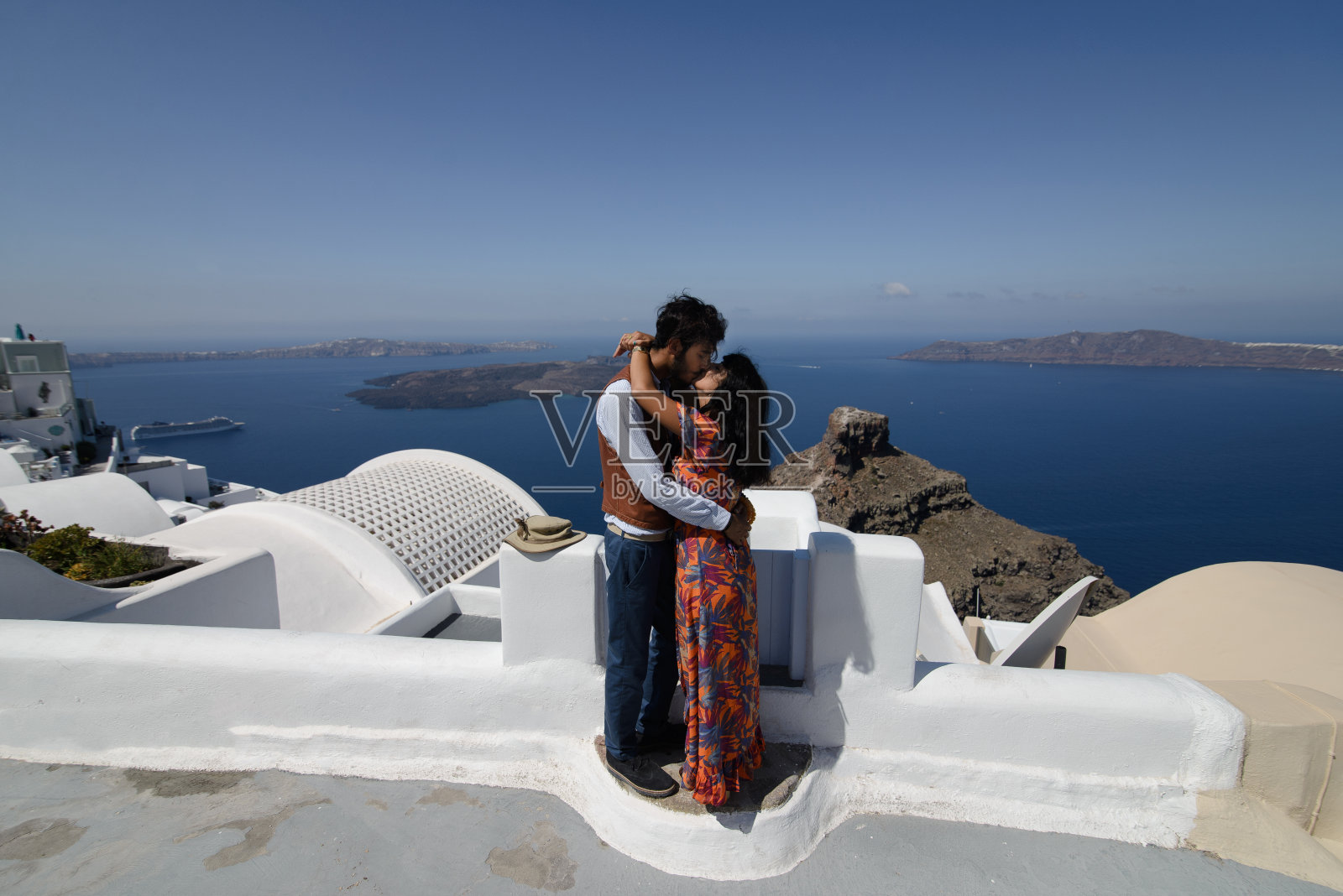 这对夫妇正坐在圣托里尼岛的屋顶上，拥抱着，大笑着照片摄影图片