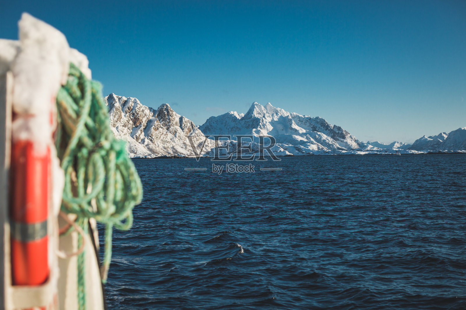 在挪威罗弗敦，绳子对着海洋和雪山。照片摄影图片