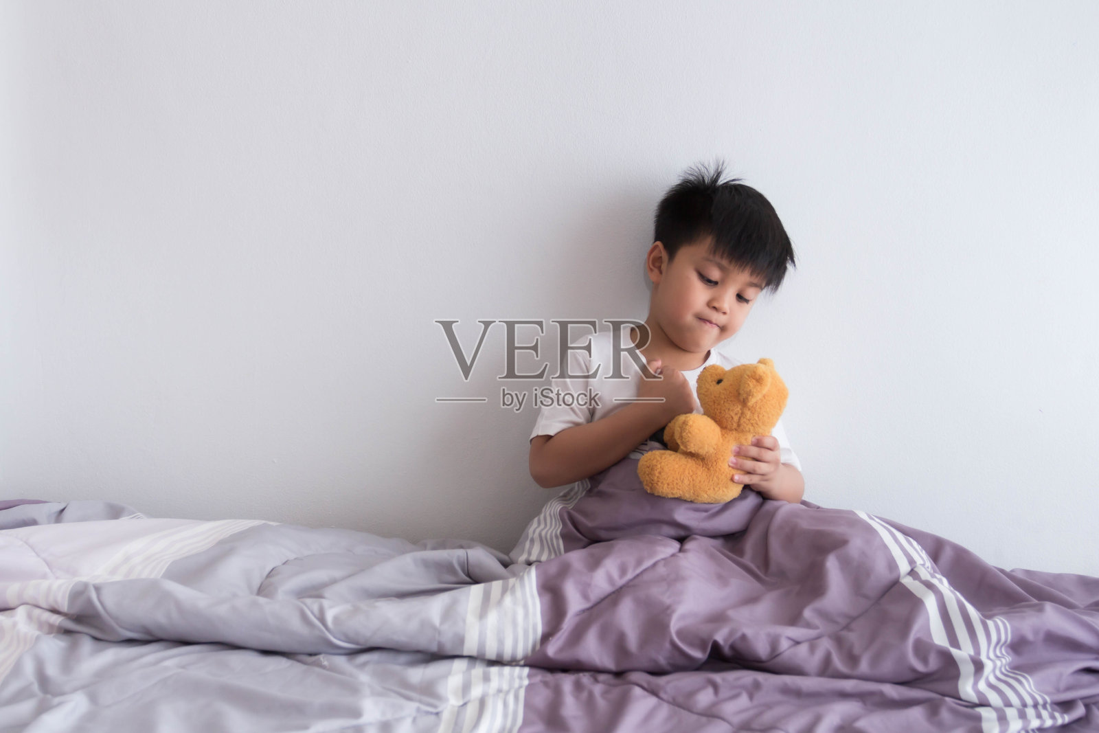 亚洲男孩和泰迪熊在他的卧室照片摄影图片