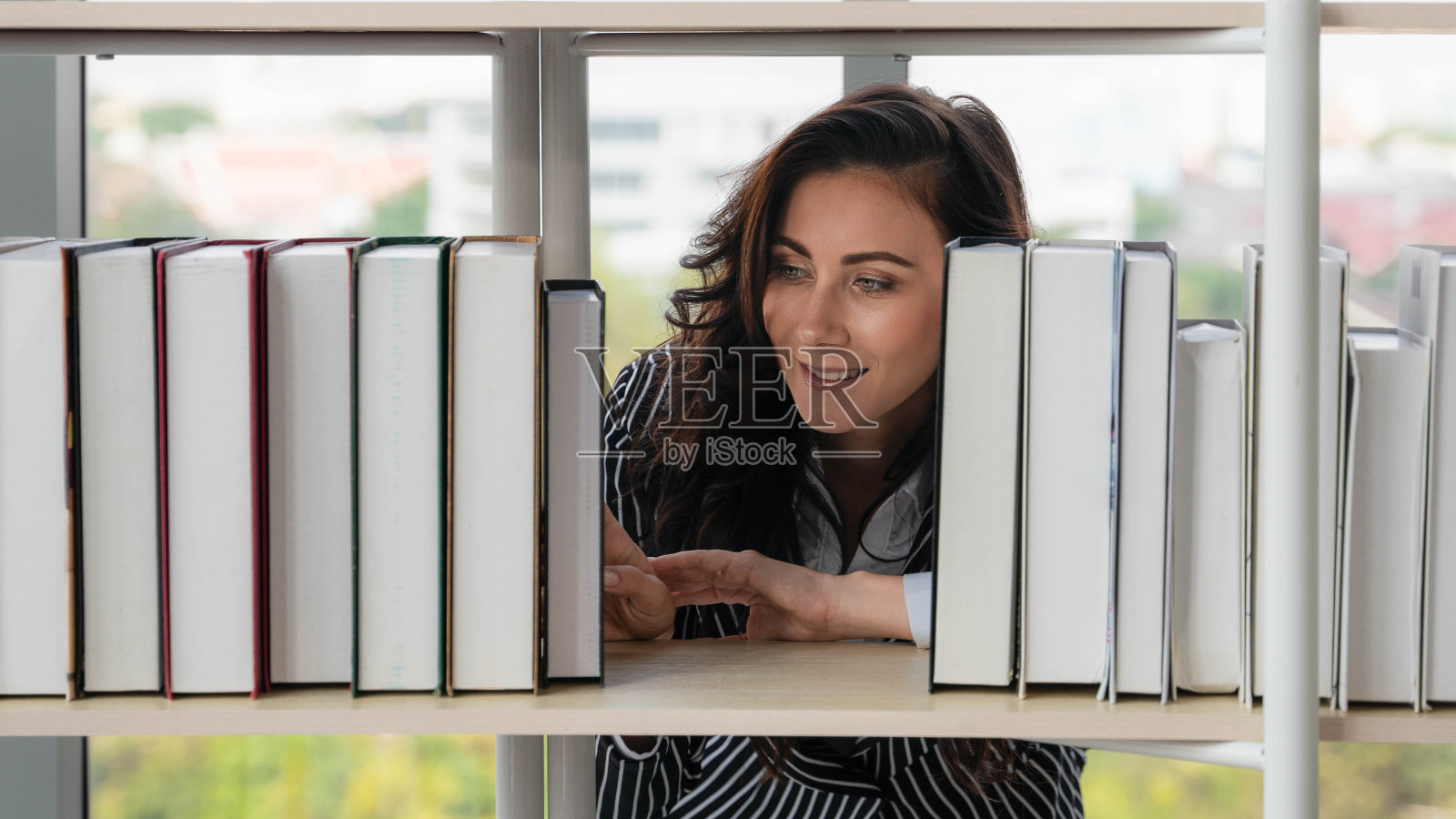 白人妇女在图书馆的书架上寻找和阅读书籍照片摄影图片