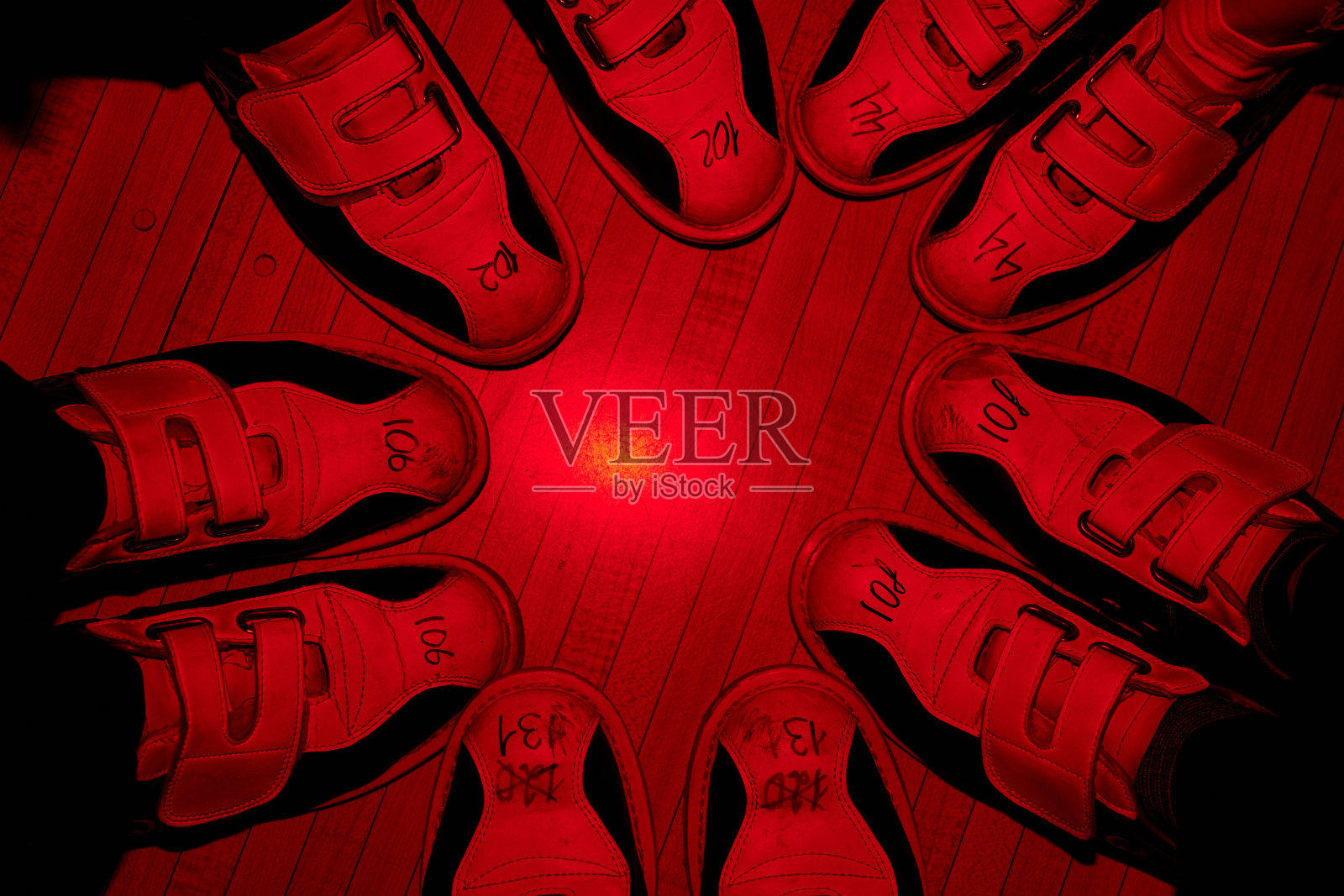 五个朋友的脚，穿着保龄球鞋，紧挨着站在地板上照片摄影图片