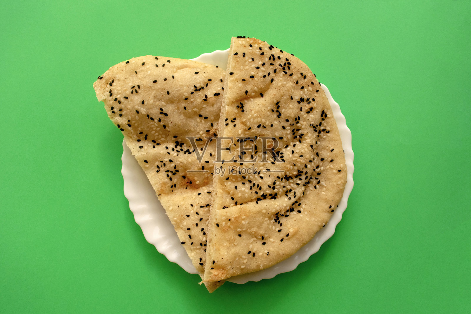 著名的传统阿拉伯皮塔饼，白色盘子上的绿色背景。照片摄影图片