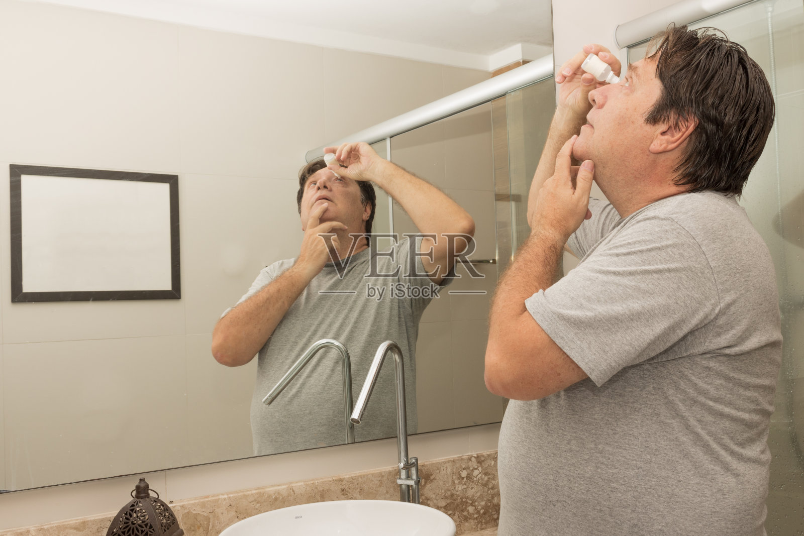 老男人在浴室滴眼药水照片摄影图片