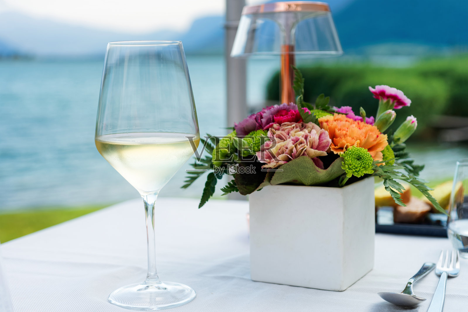 意大利卡尔达罗湖豪华街头餐厅的一杯红酒和鲜花照片摄影图片
