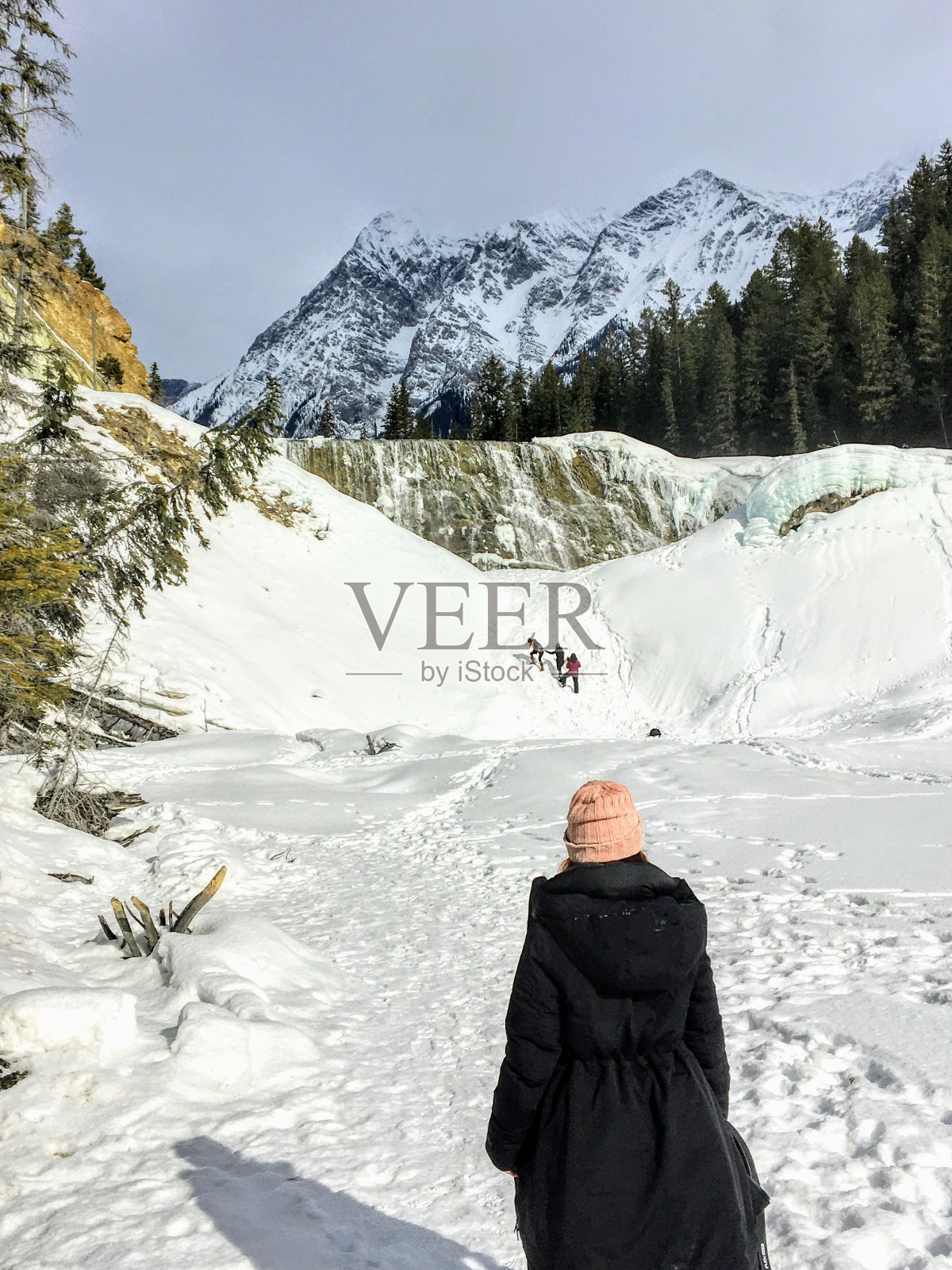 在加拿大不列颠哥伦比亚省的Yoho国家公园，一名女子正走向以落基山脉为背景的Wapta瀑布美丽的冰冻瀑布照片摄影图片