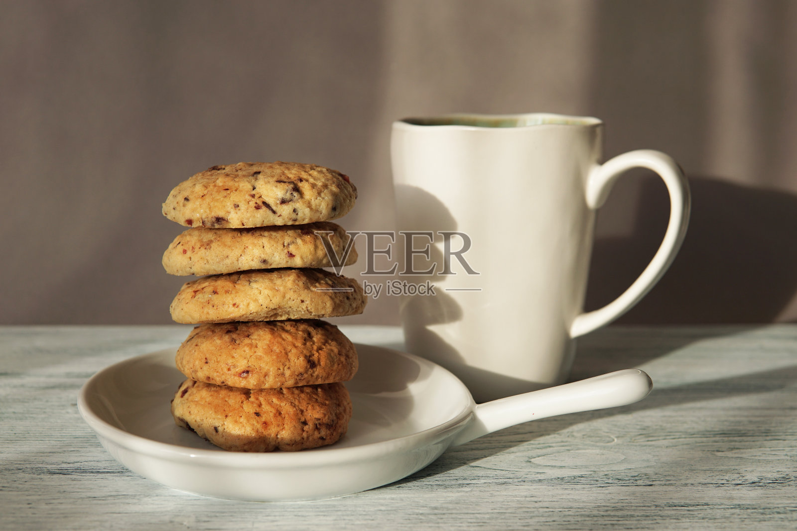 新鲜烘焙的自制饼干放在白色盘子里，配上一杯茶或咖啡。照片摄影图片