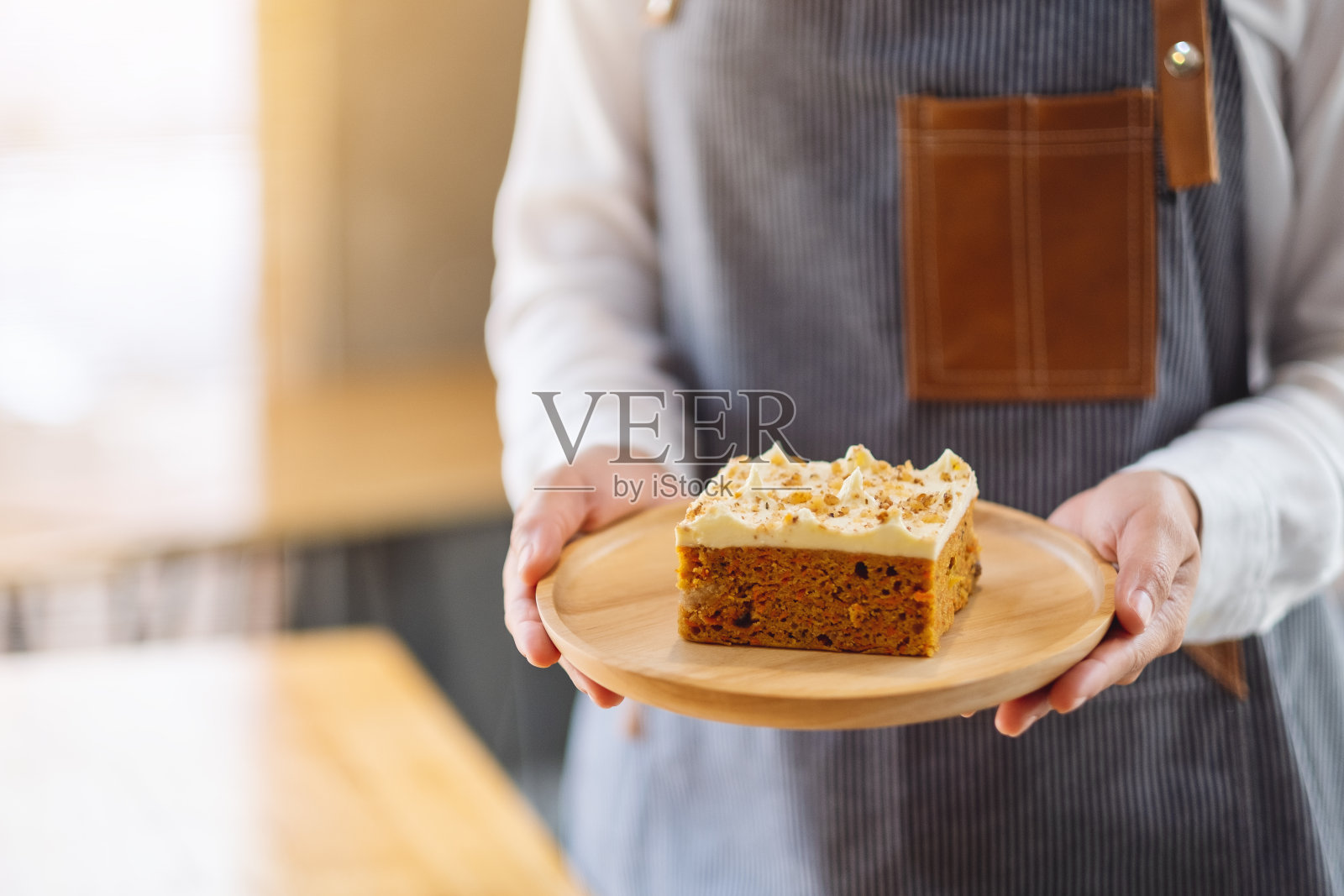 一个服务员拿着一块自制的胡萝卜蛋糕，端上餐桌照片摄影图片