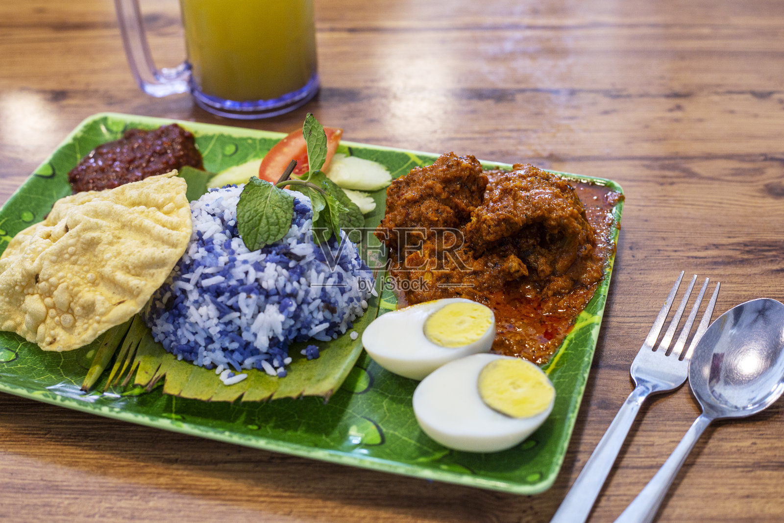 这是一种蓝色的马来米饭，上面有辣当鸡、饼干、鸡蛋和参巴照片摄影图片