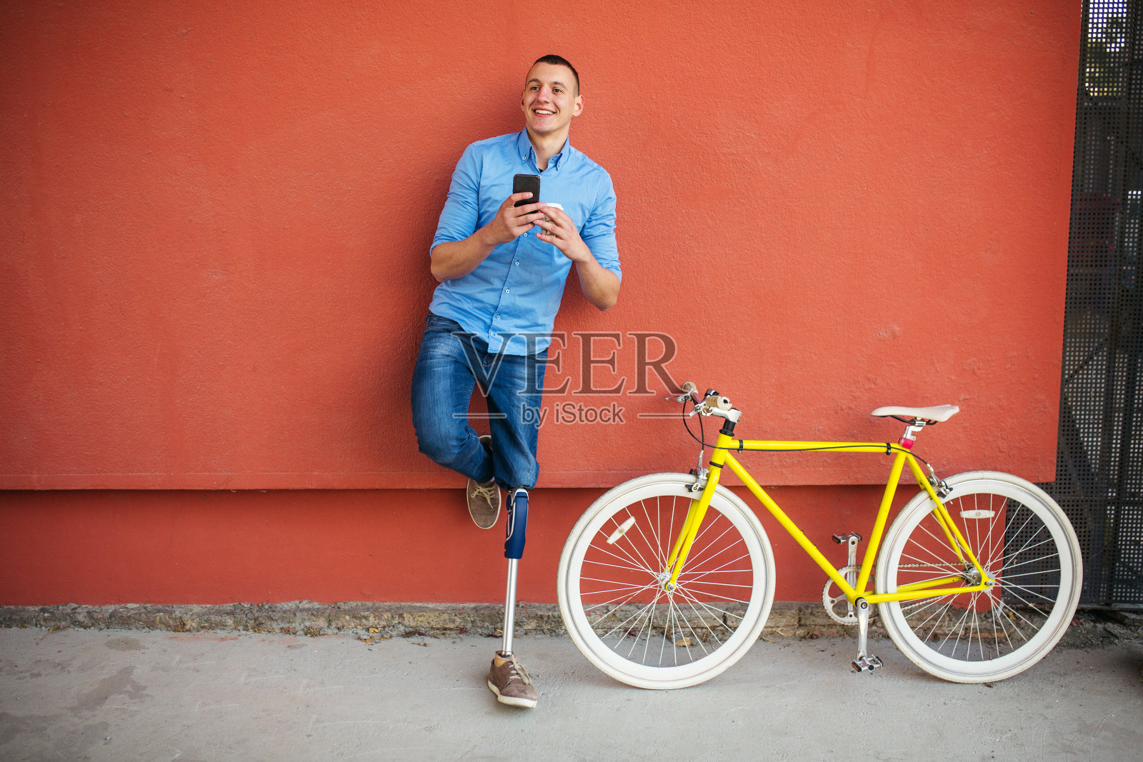年轻男性戴着假腿站在自行车旁边照片摄影图片