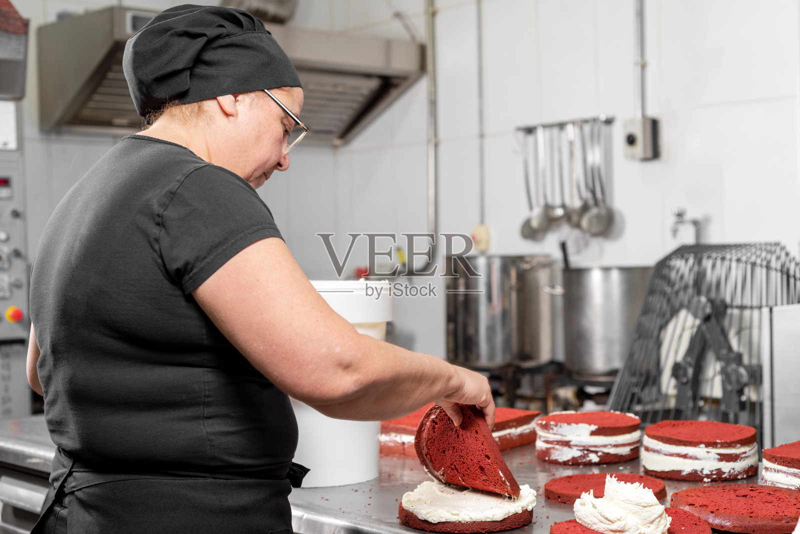 在糕点店做蛋糕的女糕点师。照片摄影图片
