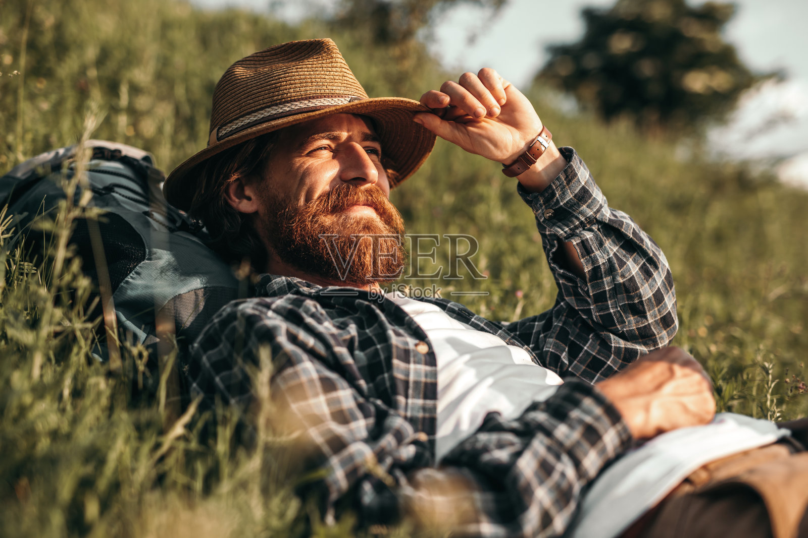 放松的男性背包客躺在草地上，在大自然中休息照片摄影图片