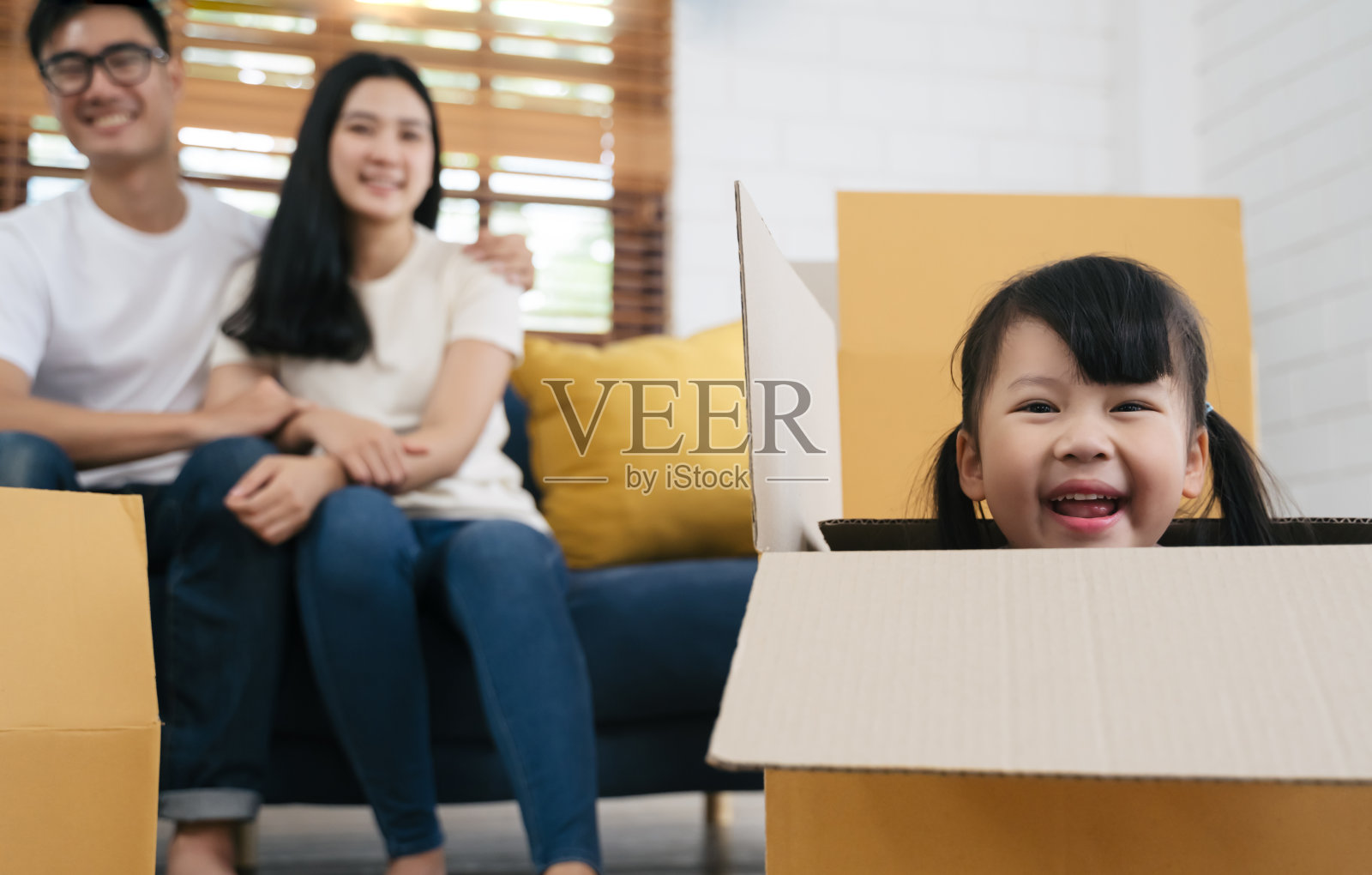 一个快乐的亚洲家庭带着纸板箱搬到新家玩纸板箱照片摄影图片