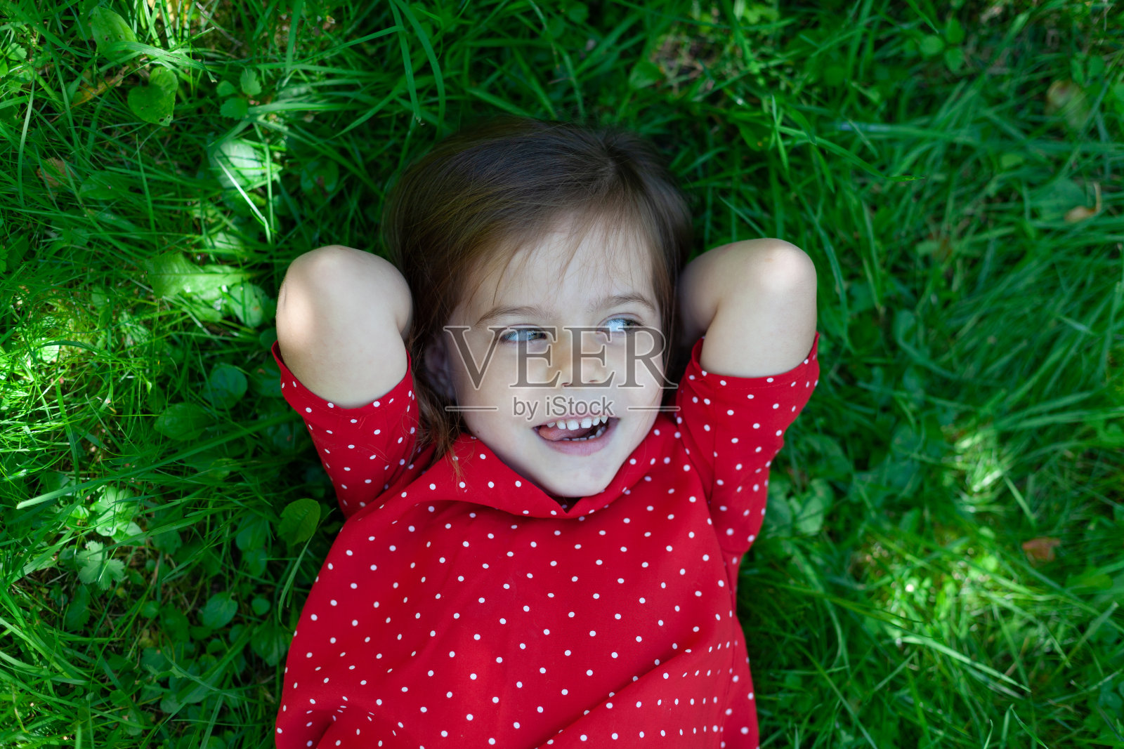 一个可爱的小女孩躺在草地上微笑的照片照片摄影图片