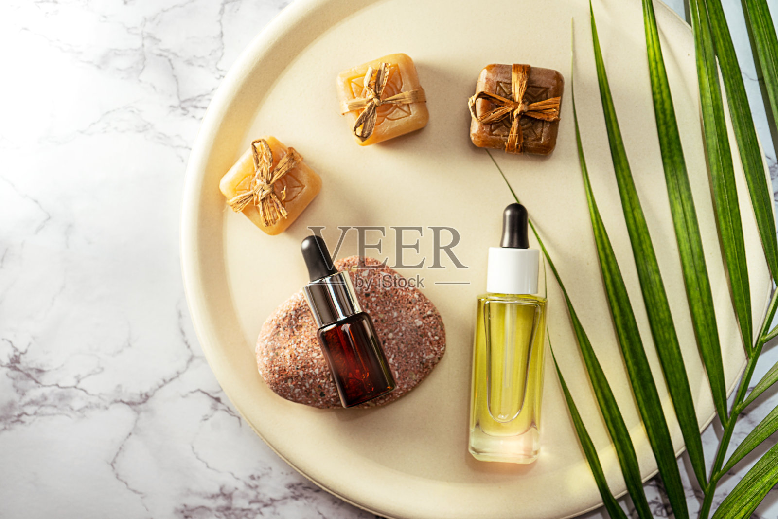 草本CBD油瓶芳香滴玻璃和棕榈叶上柔和的米色板和大理石背景。照片摄影图片