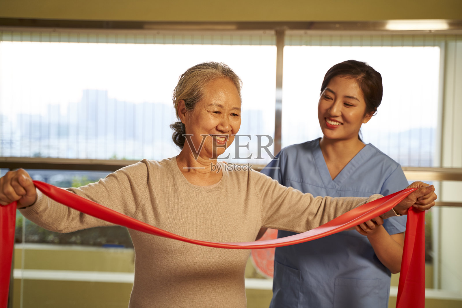 亚洲老妇人在康复中心使用阻力带锻炼照片摄影图片