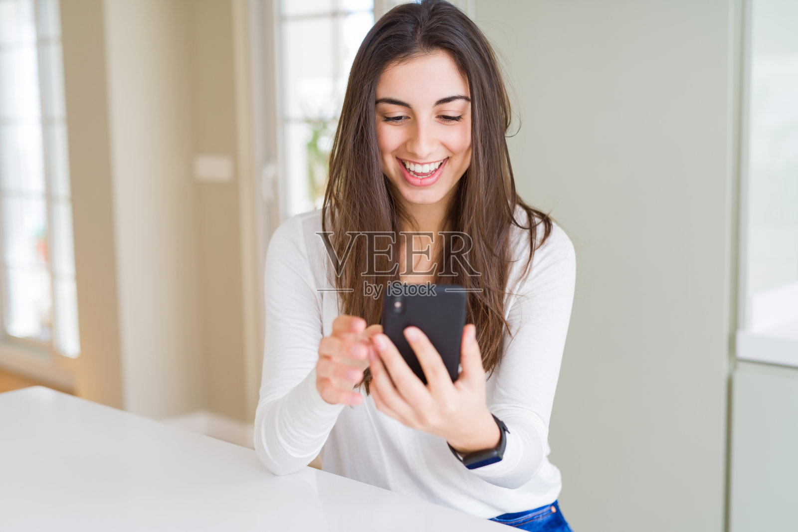 年轻女子使用智能手机，微笑着愉快地发短信和打字照片摄影图片