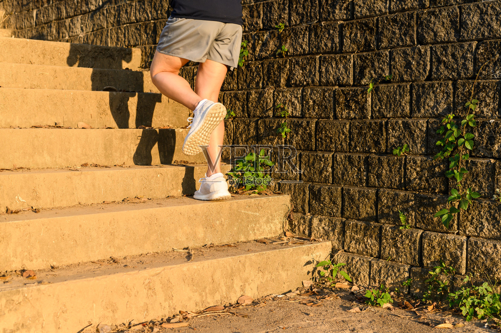 在城市街道上，女性健身运动员通过在楼梯上跑步来训练自己。照片摄影图片