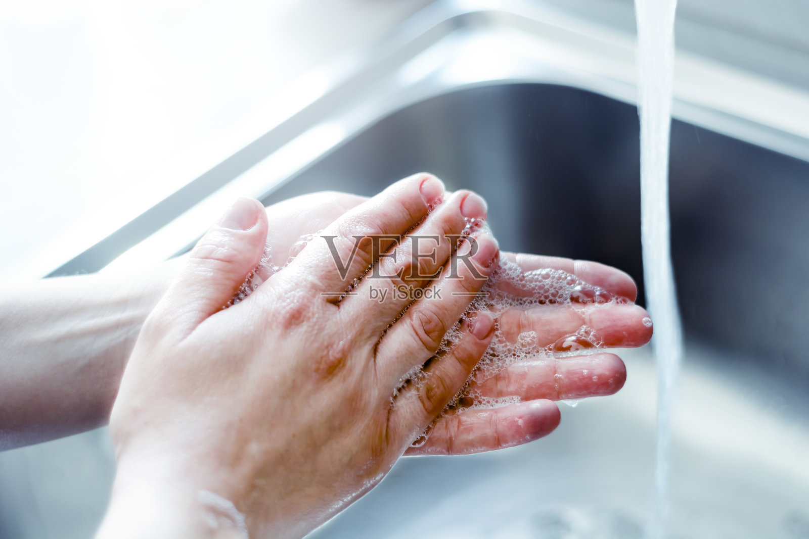 一个年轻的白人妇女用肥皂洗手。冠状病毒大流行COVID-19。保持双手清洁是最重要的步骤之一，以避免生病和传播细菌给他人。检疫照片摄影图片